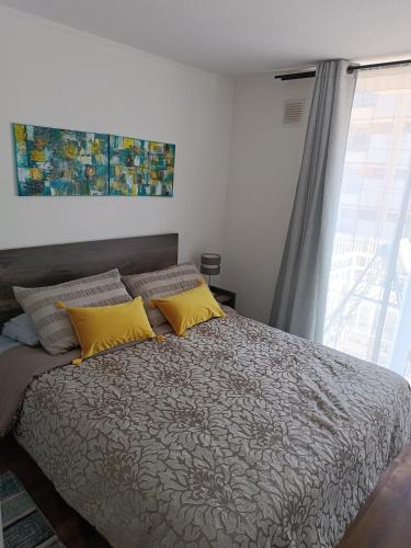 a bedroom with a bed with yellow pillows and a window at Departamento Ovalle 212 in Ovalle