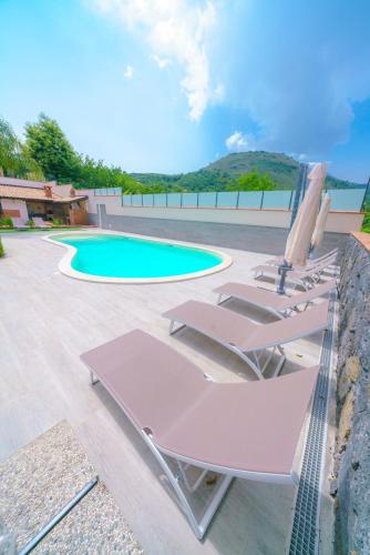 a group of lounge chairs next to a swimming pool at Bedda Mia Etna House B&B in Trecastagni