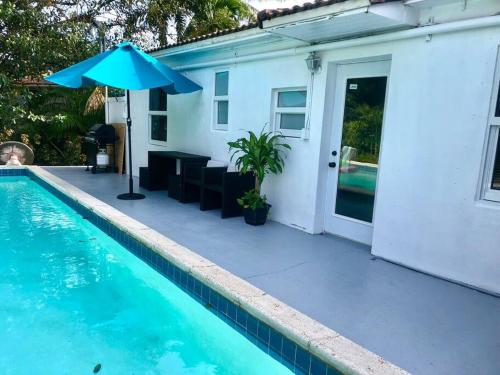 a swimming pool with an umbrella next to a house at HOUSE WITH POOL, 10 MINS DRIVE TO THE BEACH! in Miami Shores