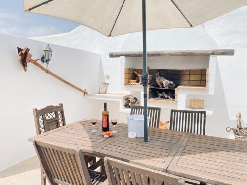 une table en bois avec un parasol sur une terrasse dans l'établissement Casa Gercko 1, à Yaiza
