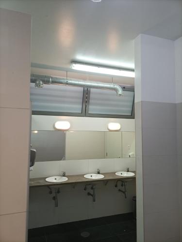 a public bathroom with three sinks and mirrors at New Wave "The best place" in Figueira da Foz