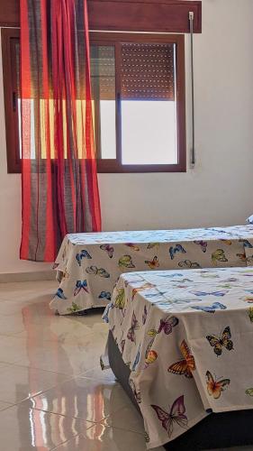 a bedroom with two beds with butterflies on the sheets at Oued Laou Apartment in Oued Laou