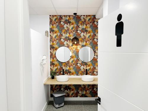 a bathroom with two mirrors and a floral wallpaper at A TROITA HOSTeL in Tui
