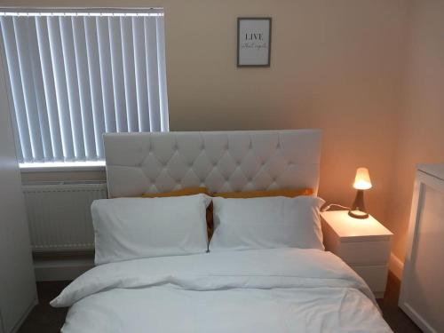 a bedroom with a bed with white sheets and a window at Beautiful and Cosy 3 beds home for 6 guests near Doncaster Racecourse 