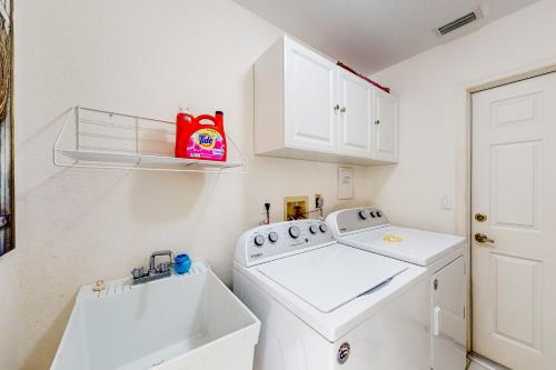 eine weiße Waschküche mit einer Waschmaschine und einem Waschbecken in der Unterkunft Koala Bungalow in Port Charlotte