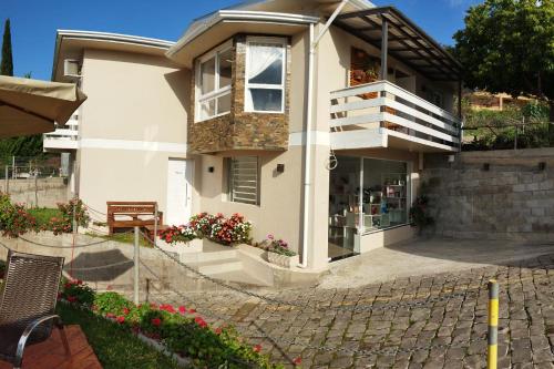 a white house with a balcony and flowers at Pousada Bella Vista - Vale dos Vinhedos in Bento Gonçalves