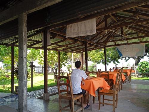 Ein Mann, der an einem Tisch in einem Restaurant sitzt. in der Unterkunft Hostal La Cascada in Mérida