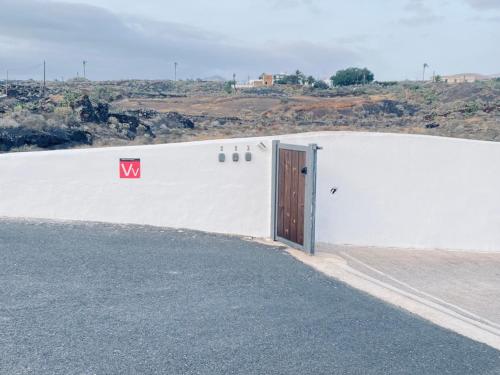 a white building with a door on the side of a road at Casa Gercko 3 in Yaiza