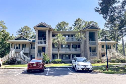two cars parked in a parking lot in front of a house at Pinehurst Condos, Unit 6-J in Pawleys Island