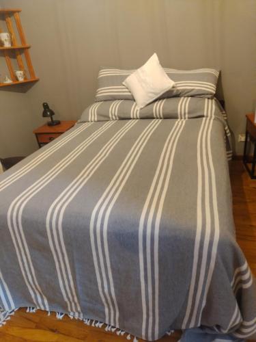 een groot bed met een blauw en wit gestreepte deken bij Loft Quilmes in Quilmes