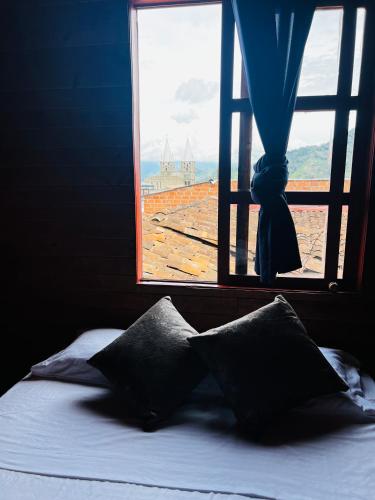 a bed with two pillows in front of a window at Casa madera in Jardin