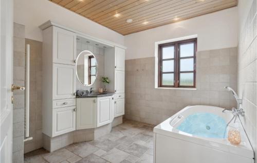 ein Badezimmer mit einer Badewanne, einem Waschbecken und einem Spiegel in der Unterkunft Amazing Home In Spjald With Wifi in Spjald