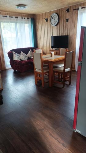 a living room with a wooden table and a couch at Cabaña los pajaritos de frutillar in Frutillar