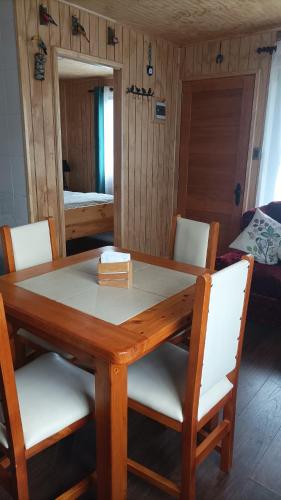 a dining room table with white chairs and a mirror at Cabaña los pajaritos de frutillar in Frutillar
