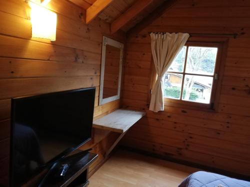 Habitación con TV y ventana en una cabaña de madera. en Cabañas Matilde 1 en San Martín de los Andes