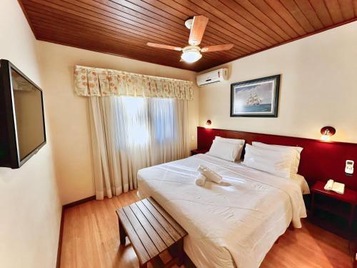a bedroom with a bed with a teddy bear on it at Natur Hotel - 700m da Rua Coberta in Gramado