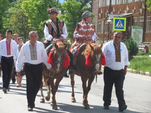 a group of men riding horses down a street at Pidkova in Verkhovyna
