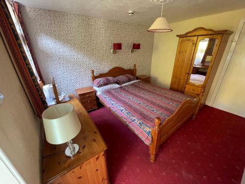 a bedroom with a bed and a lamp in it at Ben View Phoenix Hotel in Strontian