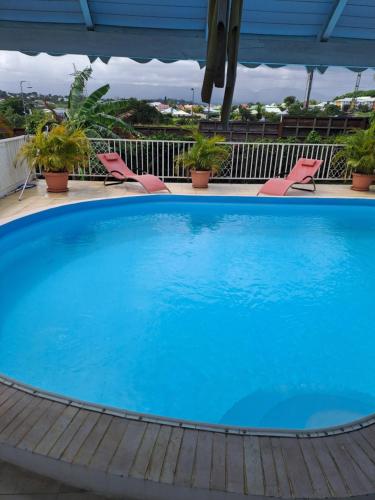 a large blue swimming pool with chairs on a balcony at VILLA LAURAYM in Baie-Mahault