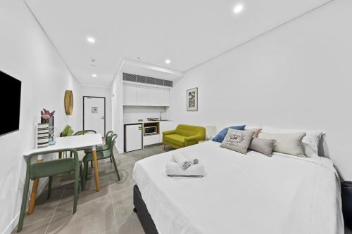 a white bedroom with a large bed and a kitchen at Arthur Hotel Bondi Junction no reception and house keeping no sofa bed in Sydney