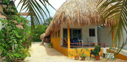 Casa blanca y amarilla con techo de paja en Cabañas La Cuchita RNT 61621, en Coveñas