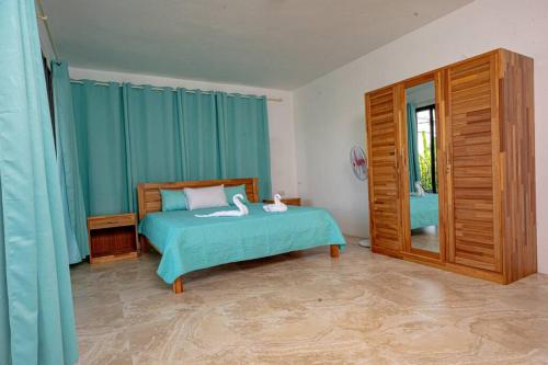 1 dormitorio con 1 cama con cortinas azules y espejo en Lotus Lane Apartments, en Grand Baie