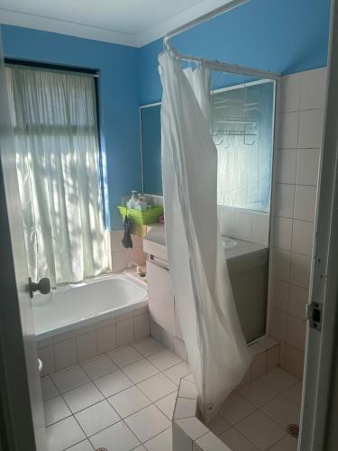 a bathroom with a tub and a shower curtain at Single room share bathroom and kitchen in Perth