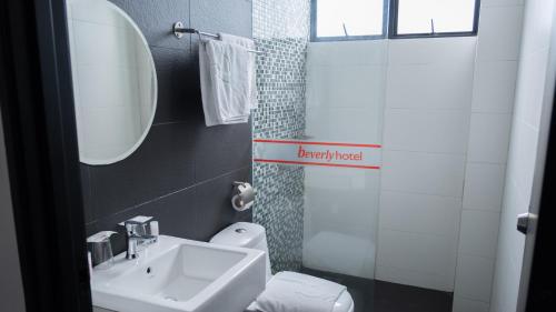 a bathroom with a sink and a toilet and a mirror at Beverly Hotel in Taiping