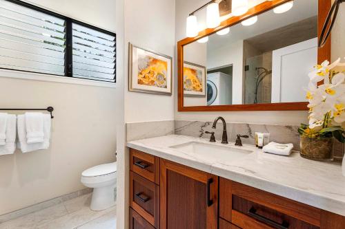 La salle de bains est pourvue d'un lavabo, de toilettes et d'un miroir. dans l'établissement Keauhou Kona Surf Racquet 2101, à Kailua-Kona