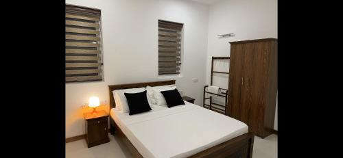 1 dormitorio con 1 cama blanca, mesita de noche y lámpara en Silina Airport Residence, en Katunayake