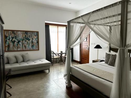 um quarto com uma cama de dossel e um sofá em The Villa by Contemporary Ceylon em Wadduwa