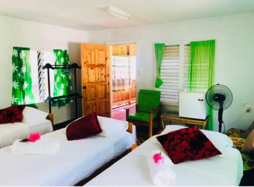 a living room with two white beds and green curtains at Apaula Heights Lounge in Apia