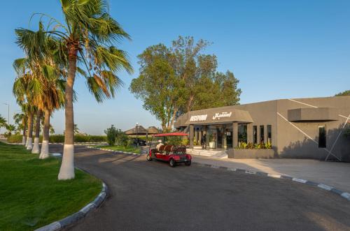 a small red car driving down a street next to a building at HDB Al Khobar Resort & Spa in Al Khobar