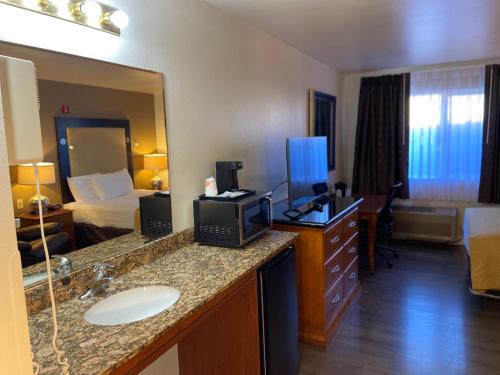 a hotel room with a bathroom with a bed and a sink at Toppenish Inn and Suites in Toppenish