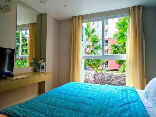 a bedroom with a blue bed and a large window at Grande Caribbean Resort in Pattaya South