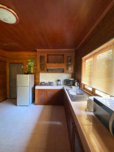 uma cozinha com armários de madeira e um frigorífico branco em Baan Laem Noi Villa's em Mae Nam