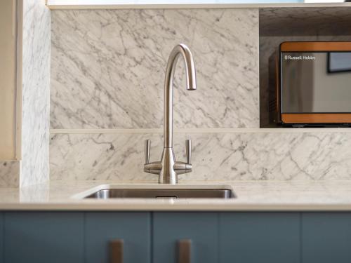 a kitchen counter with a sink and a tv at Roa Island House in Rampside