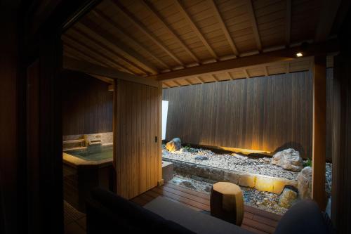 Hotel Yuraku Kyo-yasaka في Giommachi: حمام مع حوض استحمام وحديقة صخرية