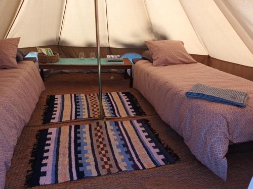 two beds in a tent with a rug on the floor at Glamping Kiveinen in Laitila