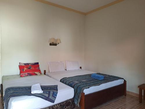 two twin beds in a room with at Kutabay Homestay in Kuta Lombok