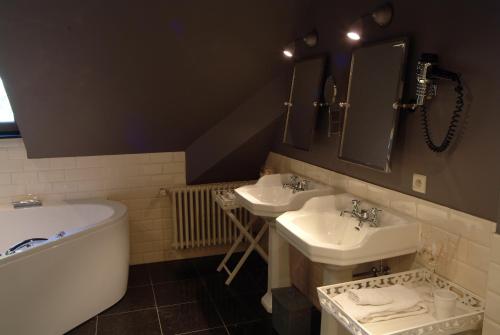 a bathroom with two sinks and a bath tub at Charmehotel Manoir Ogygia in Poperinge