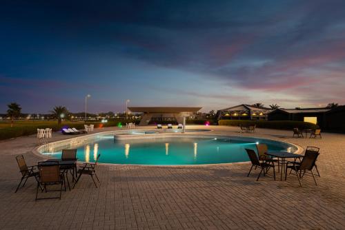 a swimming pool with chairs and a table in front of it at HDB Al Khobar Resort & Spa in Al Khobar