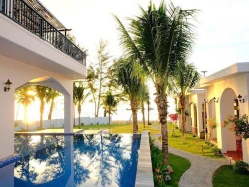 a house with a swimming pool and palm trees at Villa C62 - Private Swimming Pool 100M2 - In Stunning Sea Front Location in Mui Ne