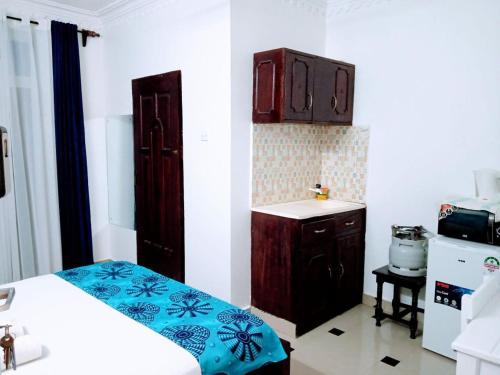 a room with a bed and a small kitchen at Lux Suites Bustani studio Apartments in Mombasa