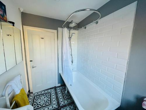 a bathroom with a white tub and a shower at The Stables Coach Home 