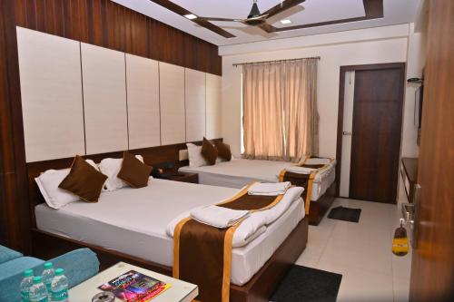 um quarto de hotel com duas camas e uma mesa em Hotel Silver Land New Digha em Digha