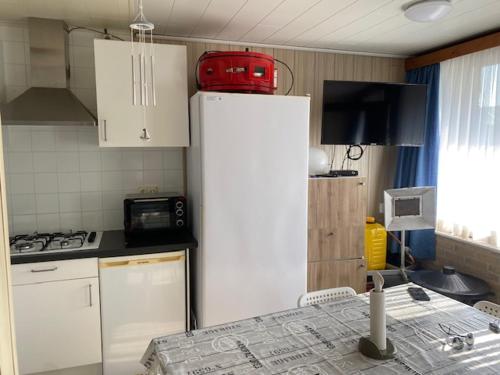 a kitchen with a refrigerator with a red suitcase on top at Camping Esmeralda in De Haan