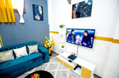 een woonkamer met een blauwe bank en een tv bij Appartement meublé in Douala