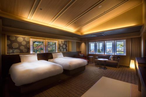 京都市にあるHotel Yuraku Kyo-yasakaのベッド2台とシッティングエリアが備わるホテルルームです。