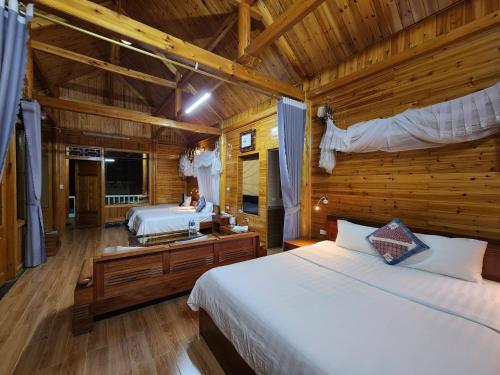 1 dormitorio con 2 camas en una cabaña de madera en Huy Trung Homestay, en Bắc Hà